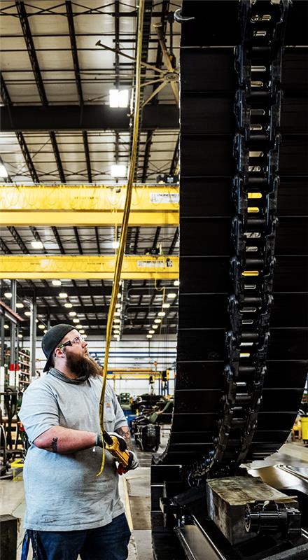 Employé de John Deere travaillant sur des chenilles d’excavatrice