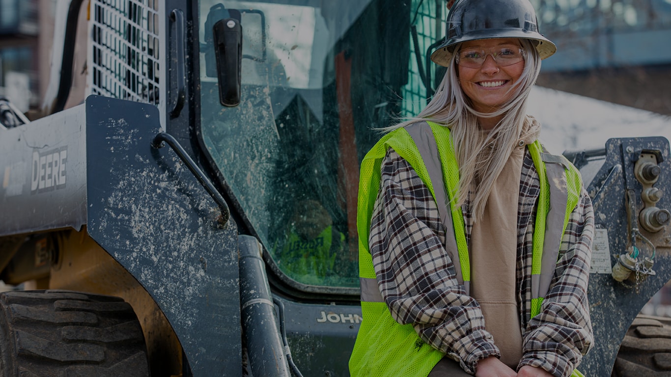 Standing in front of a 324G Skid Steer is the operator Taylor Jones