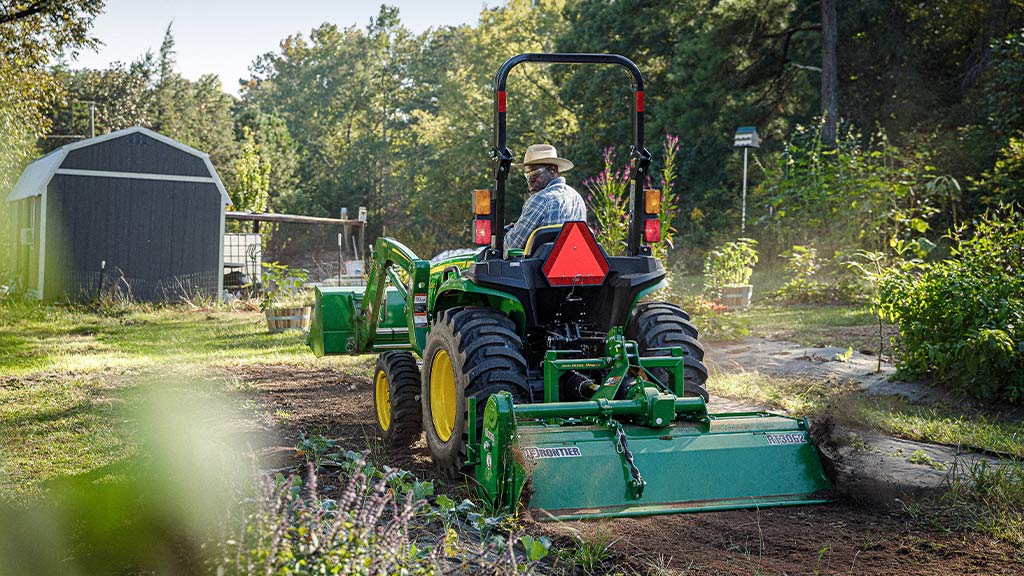 Personne qui laboure avec un tracteur 3032E et un rotoculteur RT3062 de Frontier