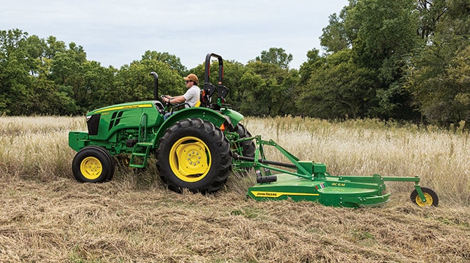 5050E tractor with attachment mowing through tall grass