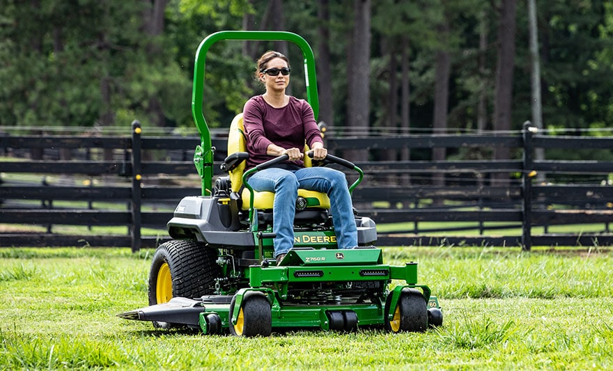 A person riding on a ztrak mower mowing the grass