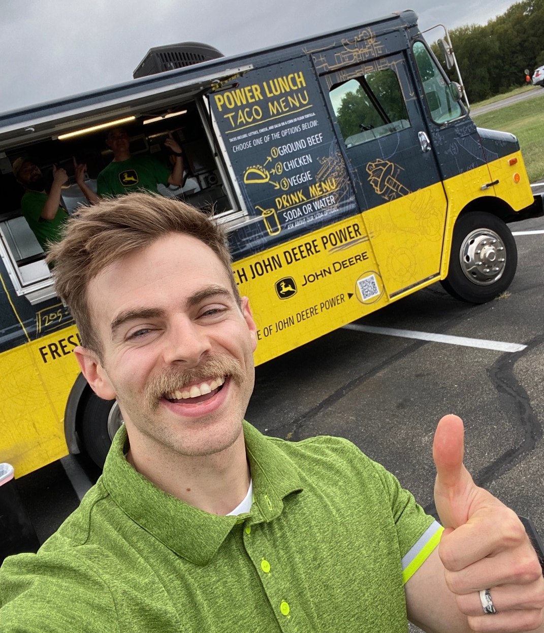 man smiling in front of the taco truck giving a thumbs up