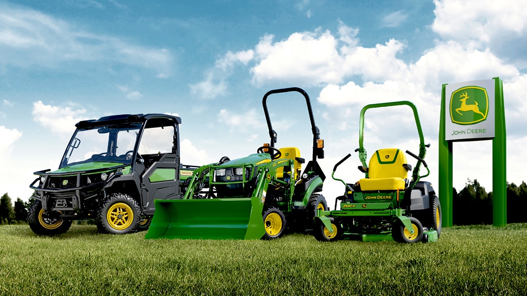 Gamme d'un Gator UTV, d'un tracteur compact et d'une tondeuse à rayon de braquage zéro devant une enseigne John Deere.