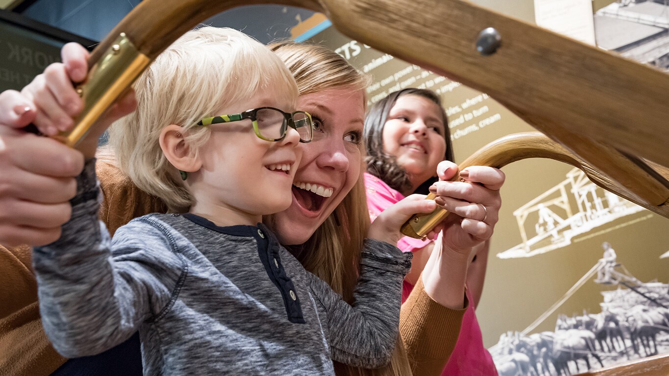Une famille jouant avec une r&eacute;plique de la charrue originale John Deere
