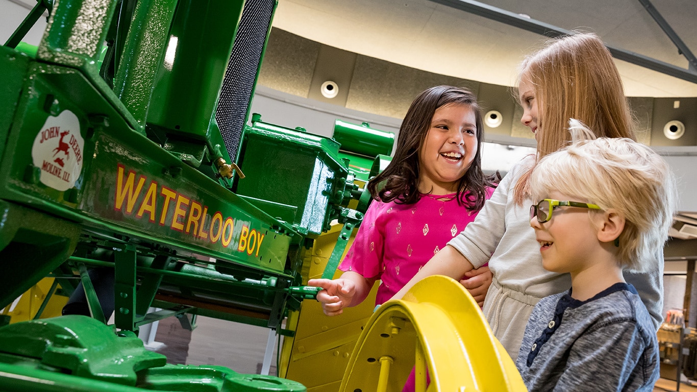 Des enfants regardant un tracteur Waterloo Boy dans l'exposition