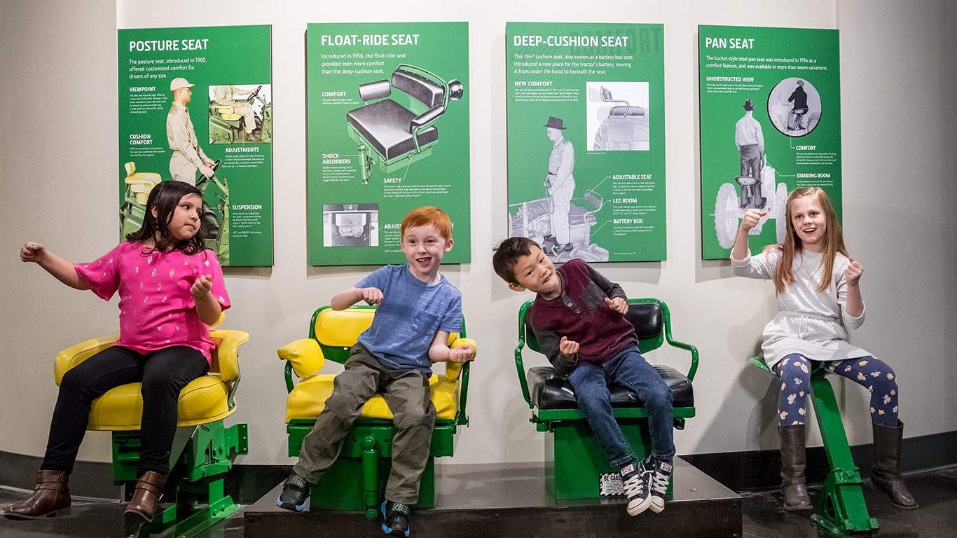 Des enfants assis sur des si&egrave;ges de tracteur de diff&eacute;rentes ann&eacute;es