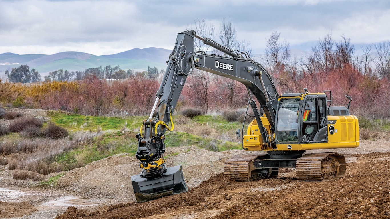 John Deere Excavator equipped with an engcon tiltrotator in motion on a work site.