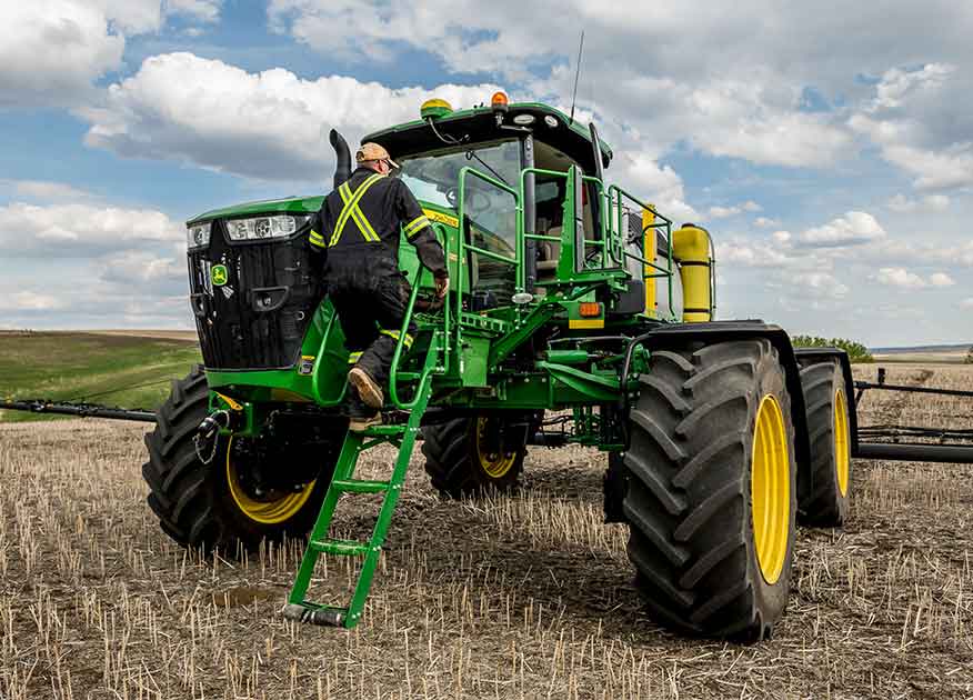 Man climbing up a John Deere tractor in a field