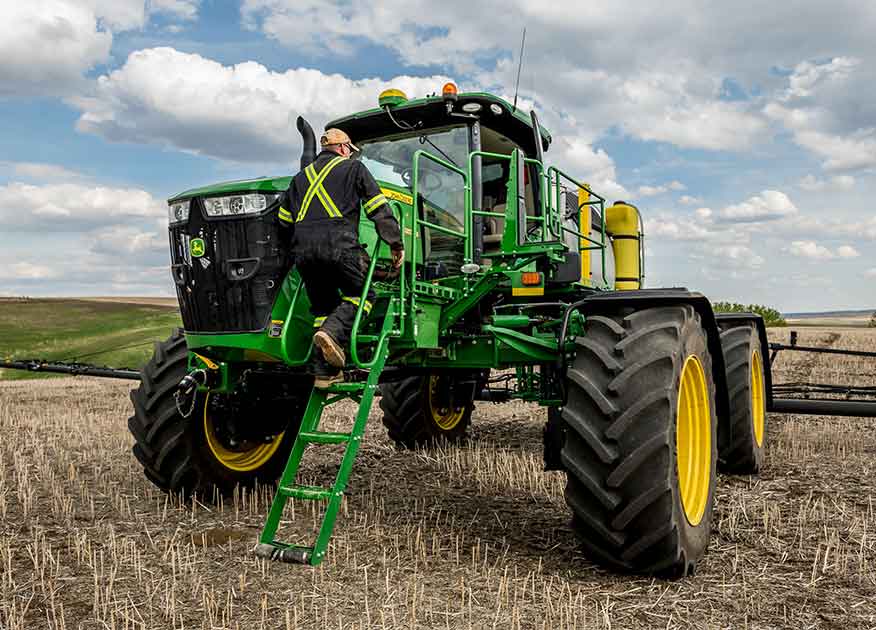 Homme montant à bord d'un tracteur John Deere dans un champ