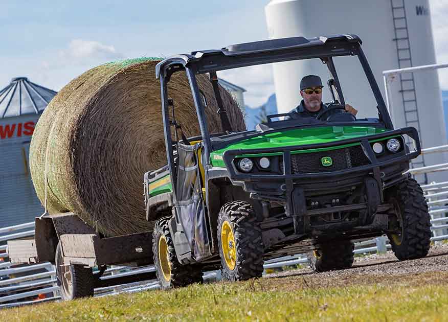 Véhicule utilitaire Gator de John Deere remorquant un ballot de foin