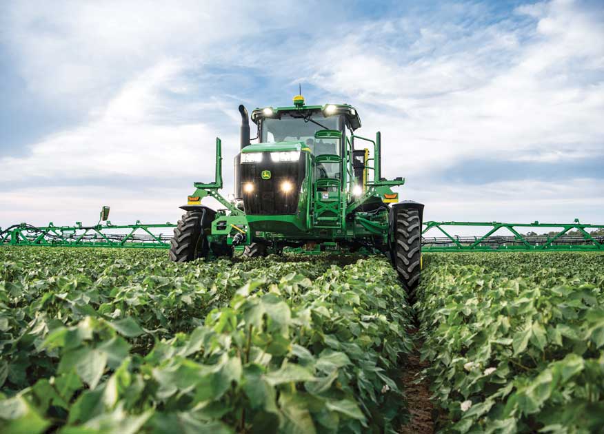 John Deere tractor and two combines working in a field