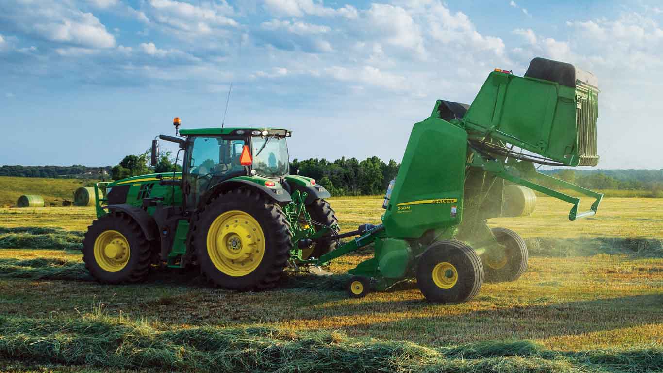 Tracteur John Deere muni d'une presse dans un champ