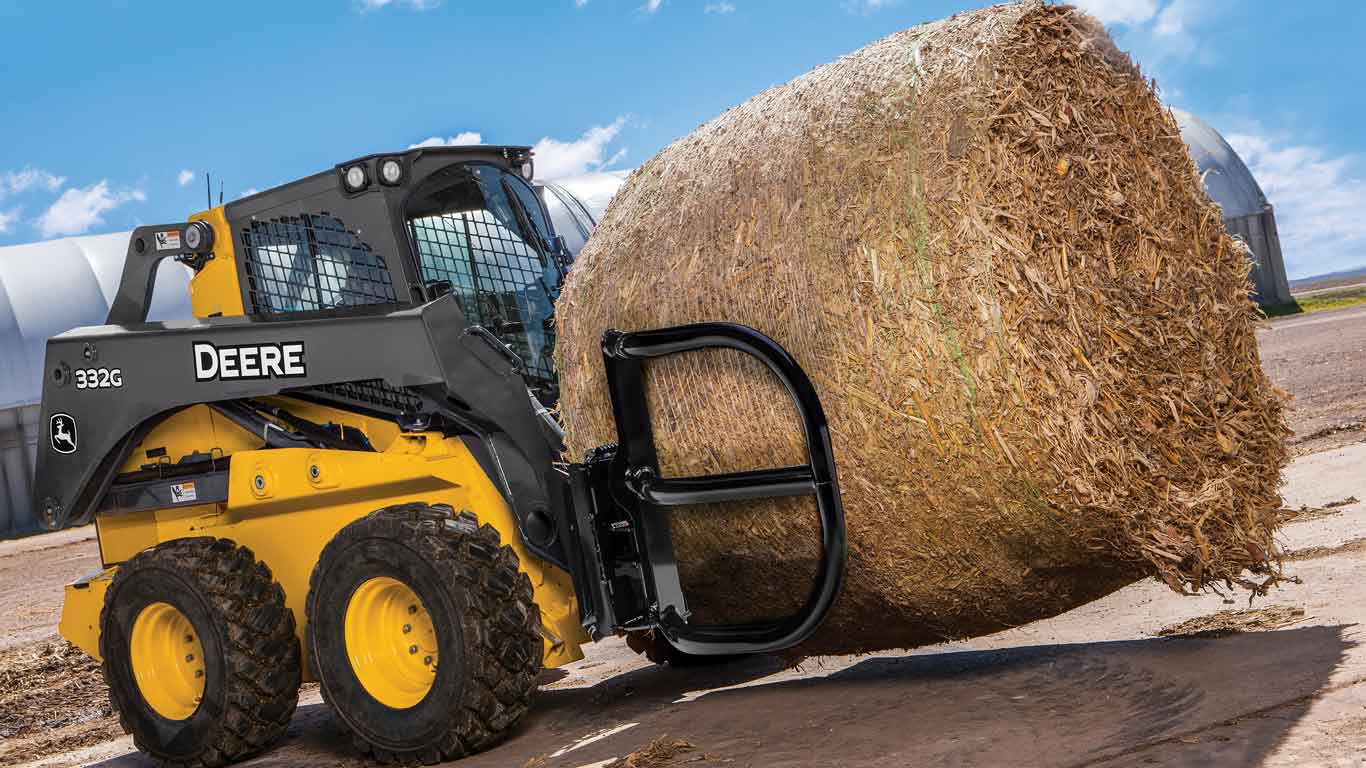 Équipement compact de John Deere soulevant une balle de foin