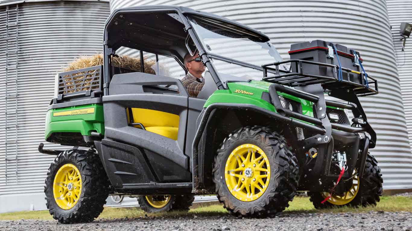 Homme à bord d'un véhicule utilitaire Gator devant une trémie à grain