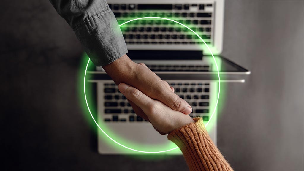 Two people shaking hands over laptop keyboards, framed by a glowing green circle.
