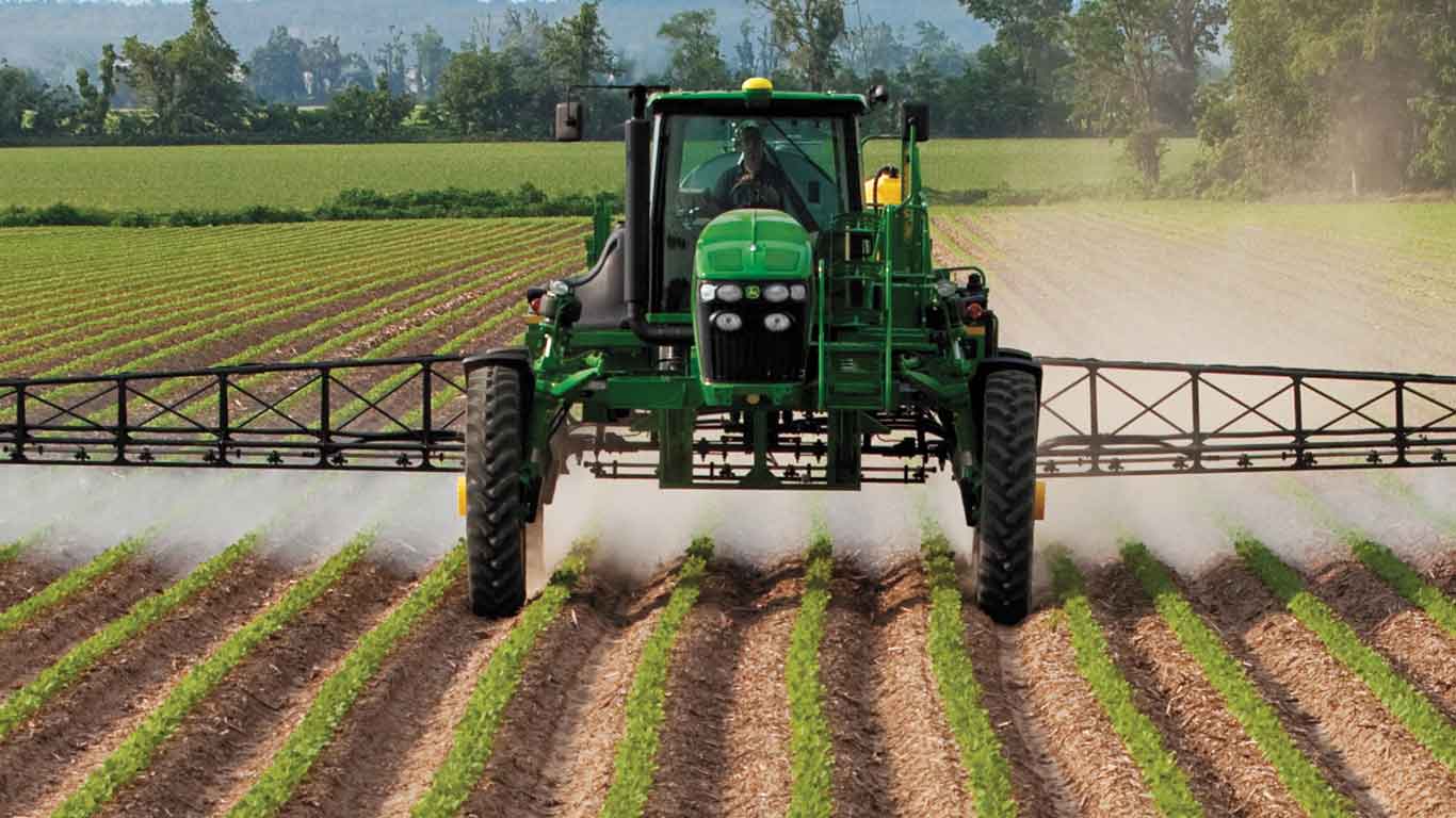 Tracteur John Deere doté d'un pulvérisateur qui fertilise un champ