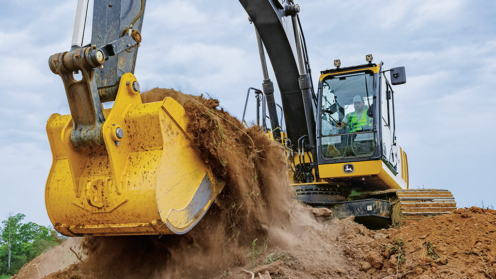 Excavatrice John Deere creusant et déplaçant du sol sur un chantier de construction.