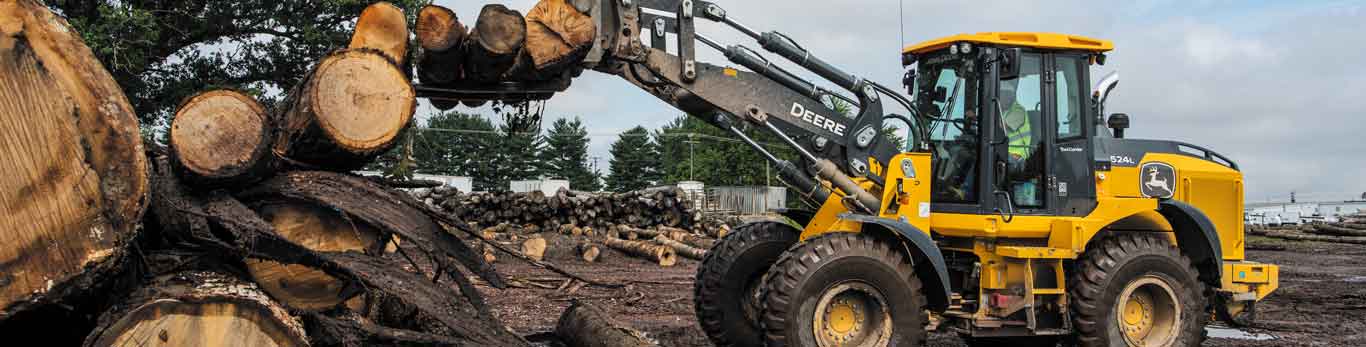 John Deere Construction equipment lifting logs onto a pile