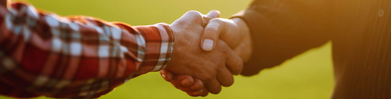 Two men shaking hands with a field blurred in the background