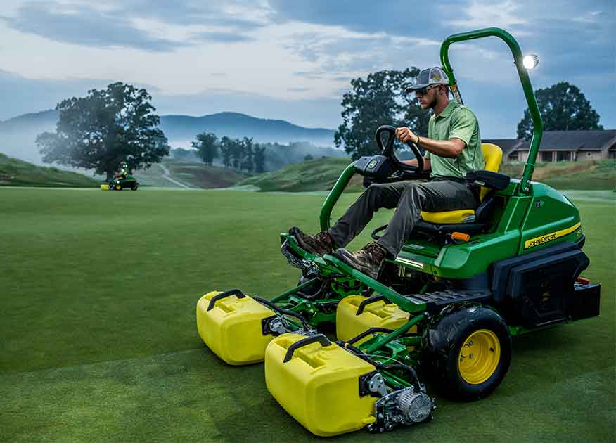 Homme utilisant de l'équipement d'entretien des terrains de golf John Deere sur un vert