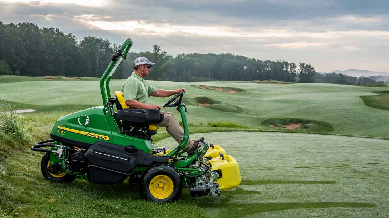 Homme utilisant de l'équipement d'entretien des terrains de golf John Deere sur un terrain de golf
