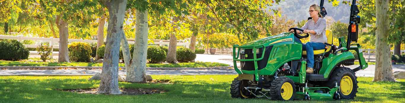 Femme conduisant un tracteur compact 1023E de John Deere