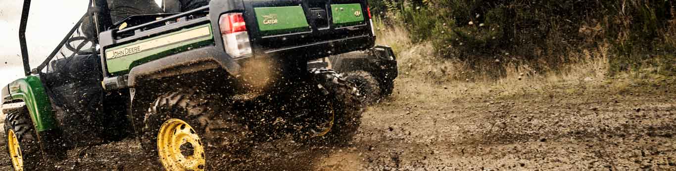 Deux personnes à bord d'un véhicule utilitaire Gator XUV 825M de John Deere parcourant un sentier