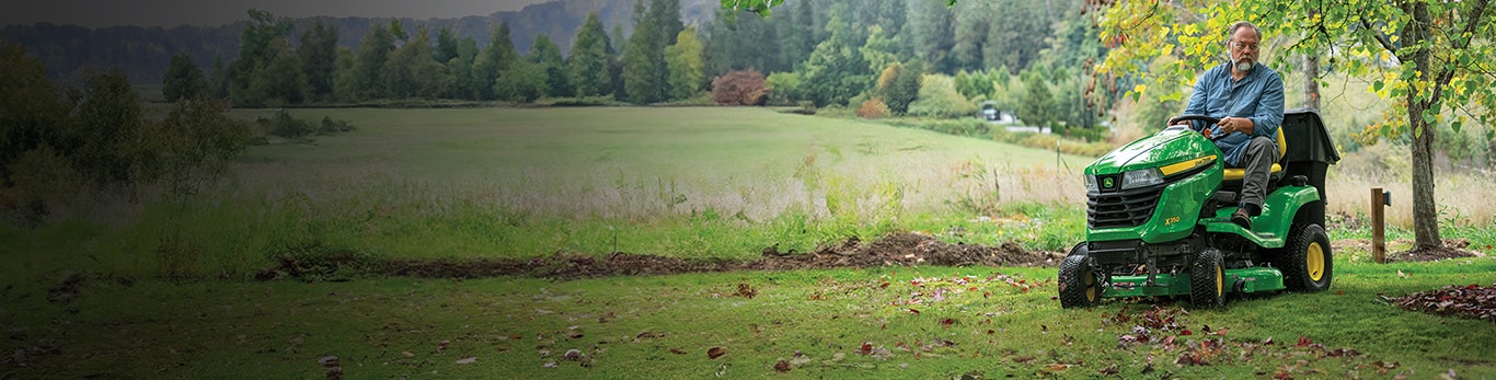 A man mowing his lawn with a John Deere X350 Riding Lawn Mower