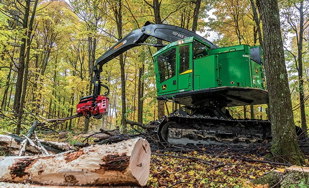 John Deere 859mh tracked harvester with IBC working in wooded area.