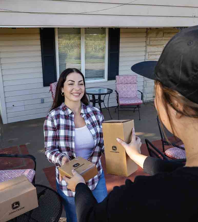 Person handing boxes with John Deere logo to another person