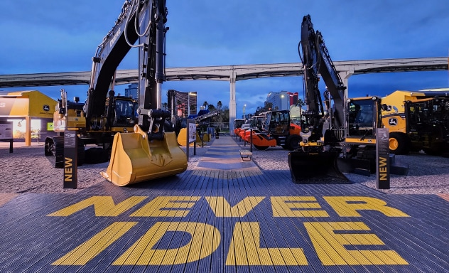 Deux excavatrices John Deere avec le slogan « NEVER IDLE » peint au sol devant leurs godets