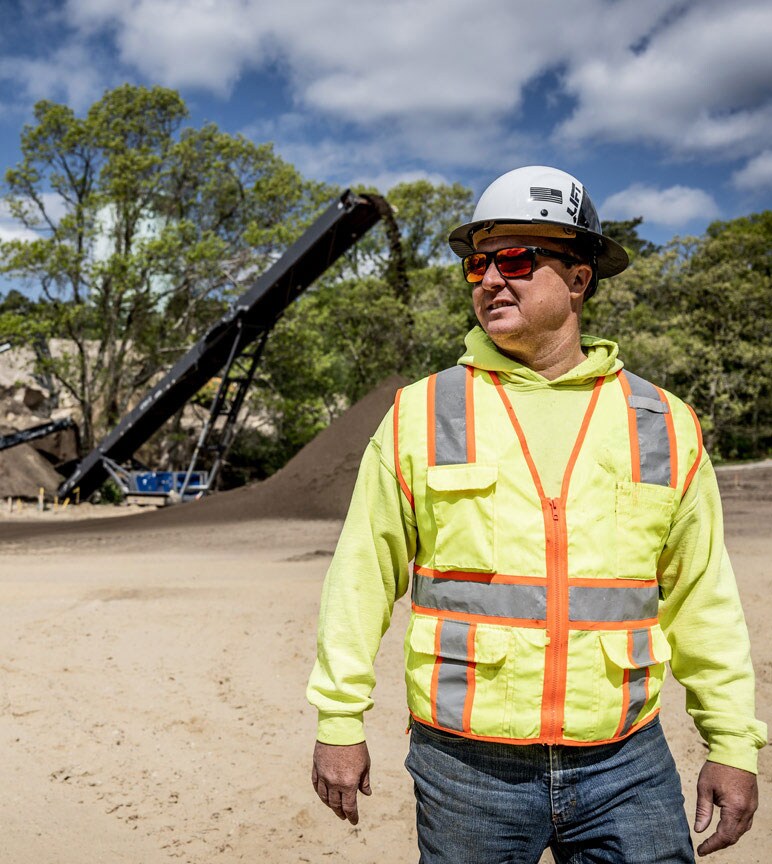 An operator stands in front of a stockpile of dirt on a worksite.