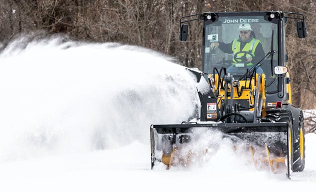Équipement John Deere muni de l'accessoire souffleuse à neige en train de déblayer de la neige