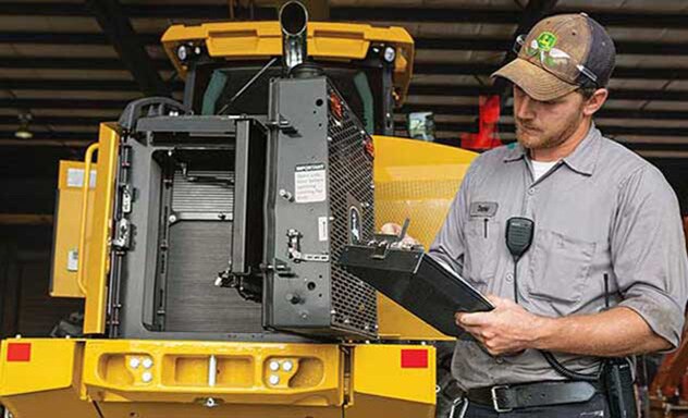 Technician with clipboard inspects a loader