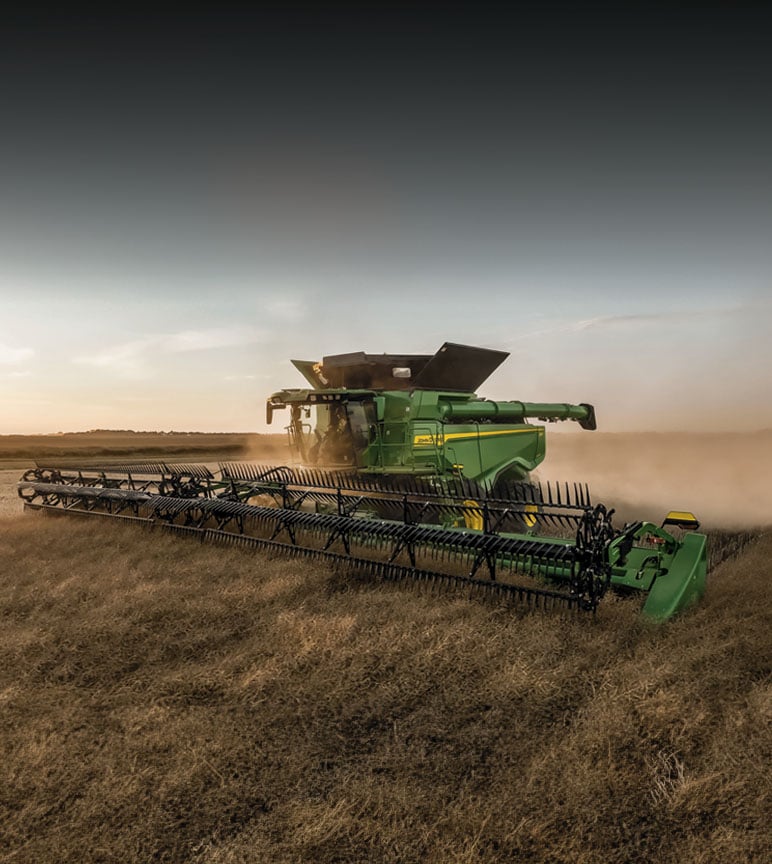 Les moissonneuses-batteuses John Deere récoltent du blé au coucher du soleil