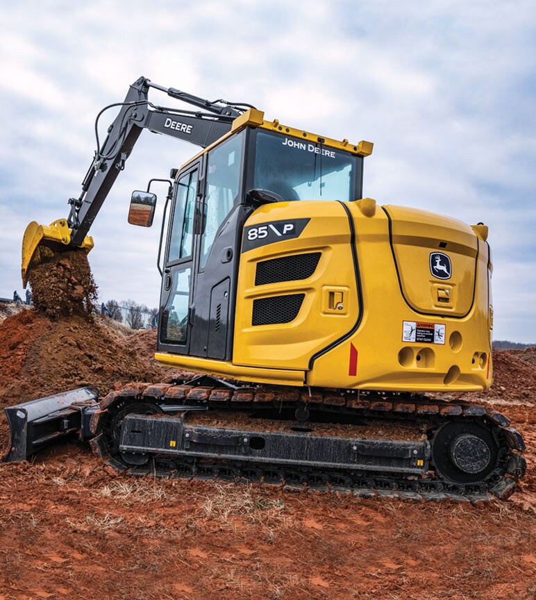 Excavatrice de catégorie P 85 de John Deere qui déplace de la terre avec un godet sur un chantier.