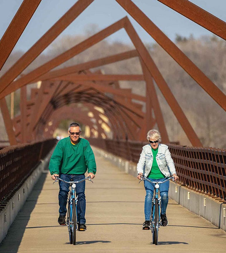 Man and woman riding bicycles on a bridge