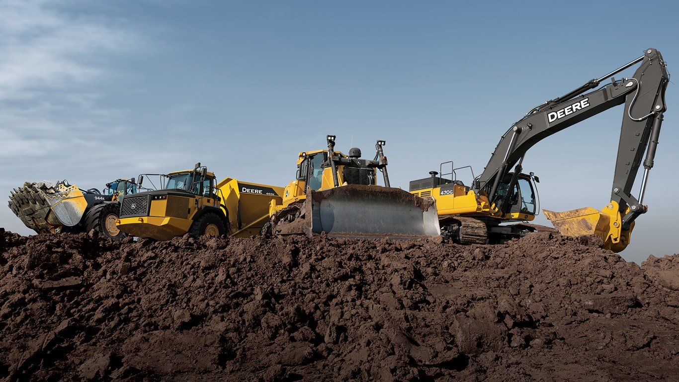 John Deere heavy construction equipment parked on dirt hill.