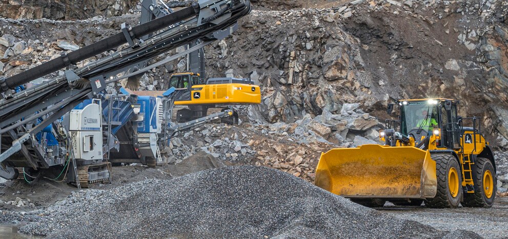 Une excavatrice et une chargeuse à roues John Deere ainsi qu’un concasseur Kleemann à l'oeuvre dans une carrière de roche