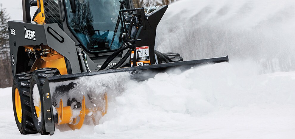 Chargeuse à direction différentielle&nbsp;326E équipée d’une souffleuse à neige chassant la neige d’une route
