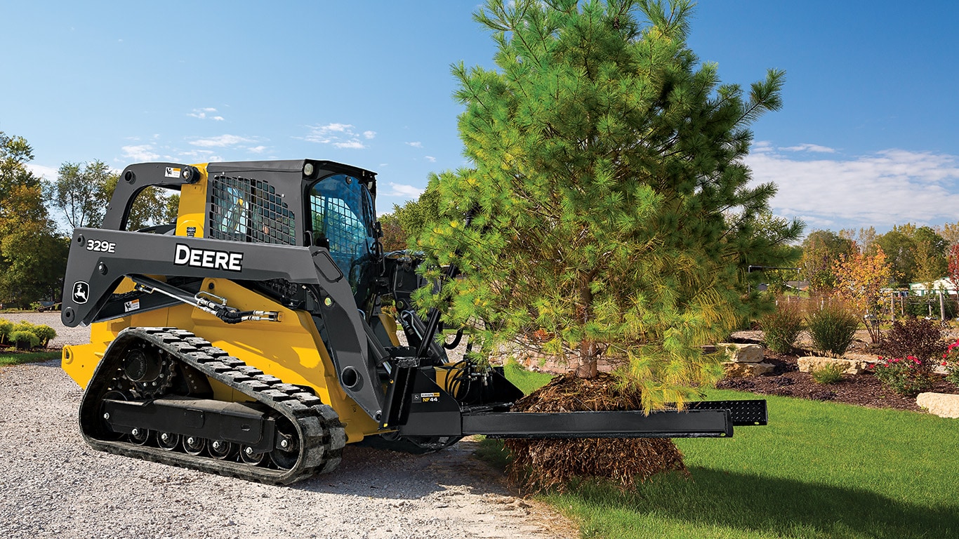 329E Compact Track Loader with nursery fork attachment relocating a pine tree.