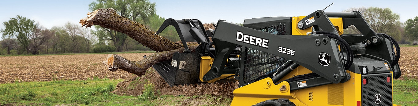 323E Compact Track Loader with Grapple attachment moving large tree branches