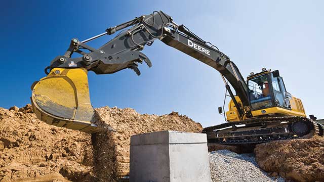 Sur un chantier de construction, une excavatrice John Deere effectue des travaux souterrains pour les services publics.