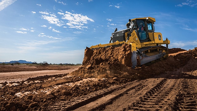 : Un bouteur John Deere pousse de la terre pour construire des routes et des plateformes sur un chantier destiné à l’aménagement résidentiel.