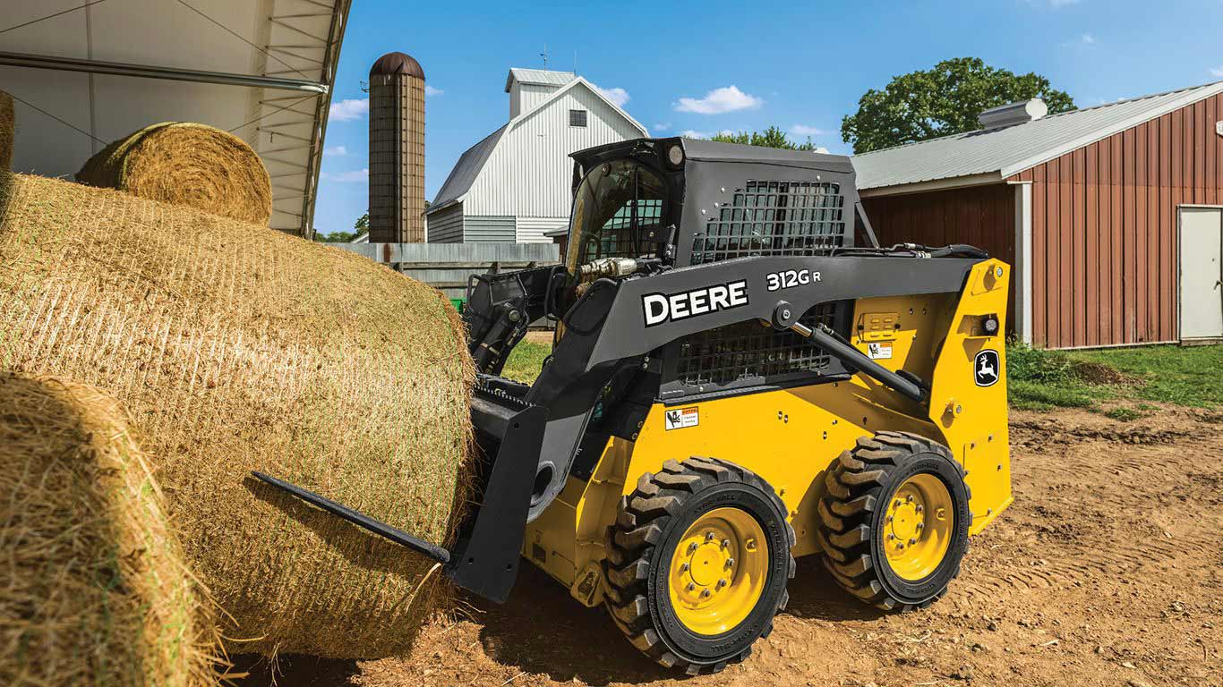 Skid steer on a farm moving a hay bale