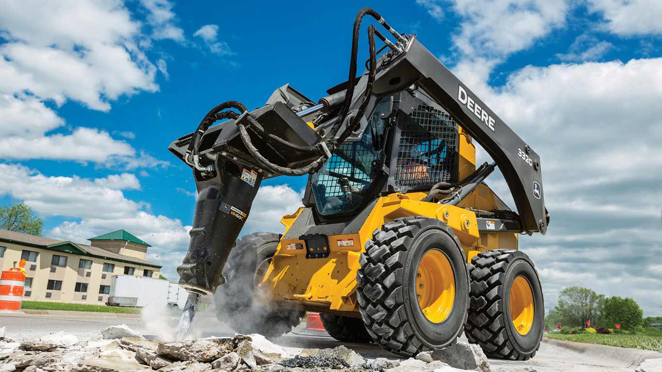 Skid steer with hydraulic hammer breaking up a road