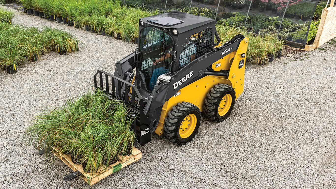 Skid steer moving a pallet of plants