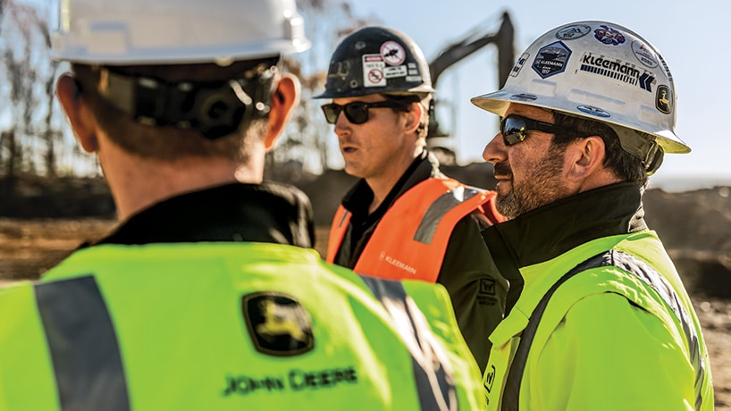 Les dirigeants d’une entreprise de construction discutent de leurs plans d’avenir avec le représentant de leur concessionnaire John Deere.