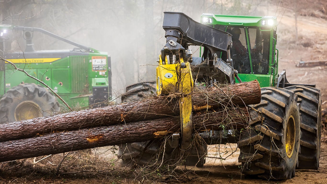 John Deere skidder moving logs in forest