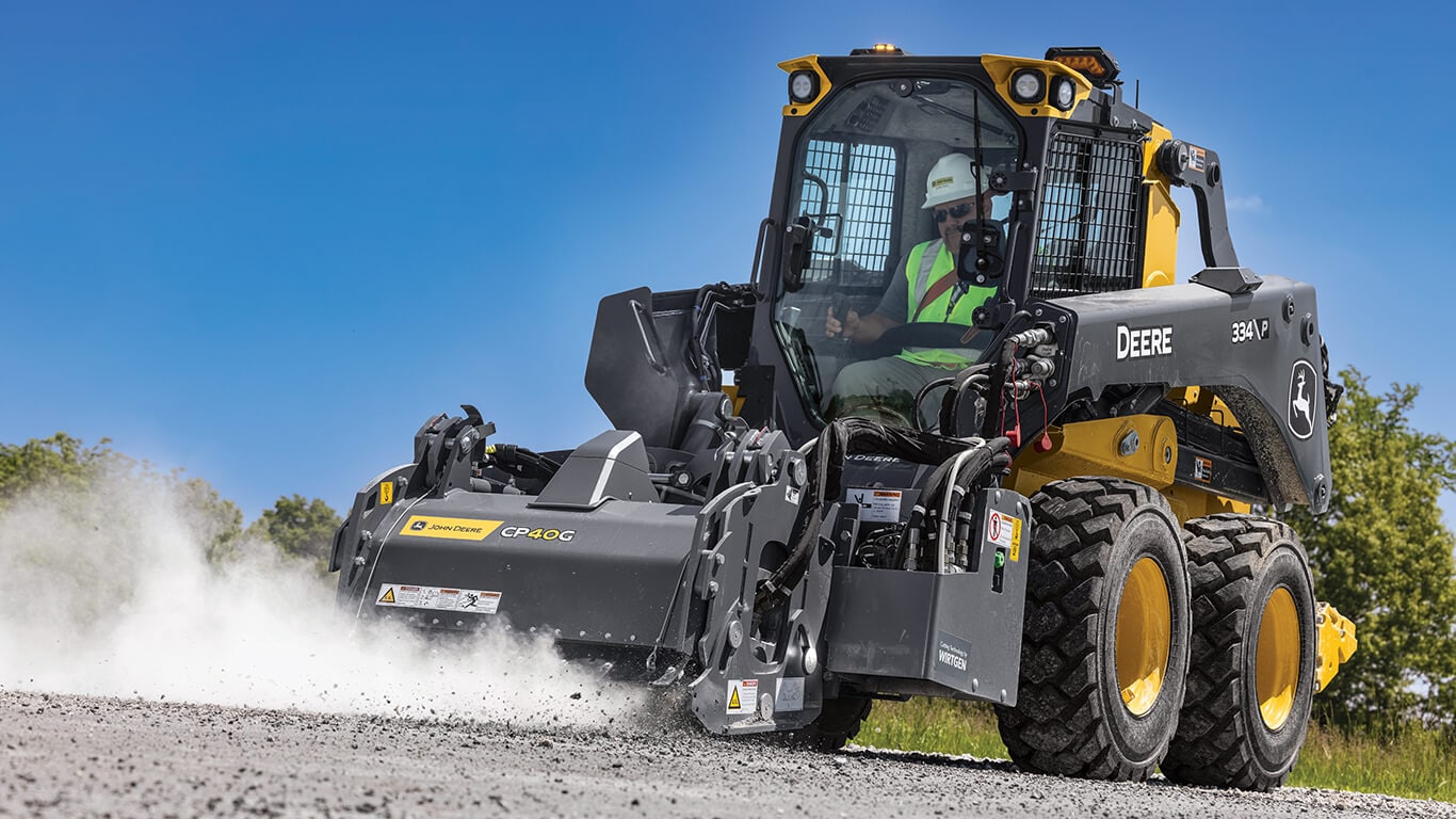 334 P-Tier skid steer using CP40G cold planer attachment to clean and level road.